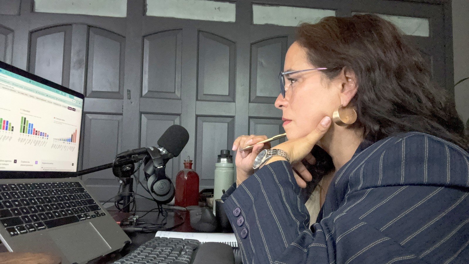 Adriana Díaz trabajando frente a una pantalla con datos, con anotaciones a mano.