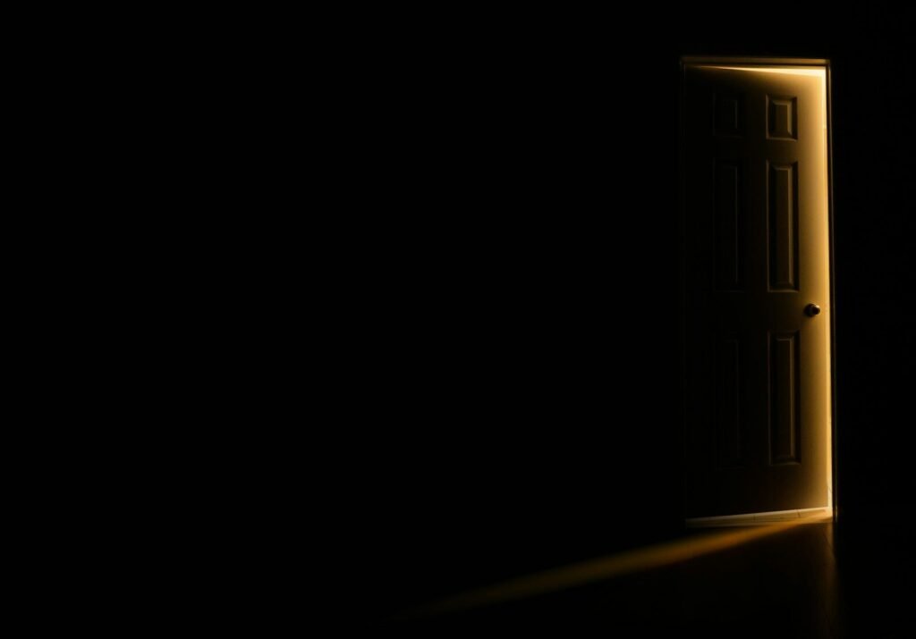 Puerta entreabierta con luz cálida entrando en una habitación